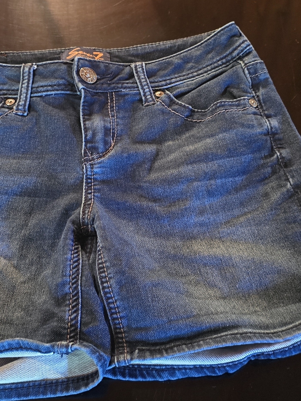 Seven7 denim shorts feature distinctive embroidered back pockets and a dark blue